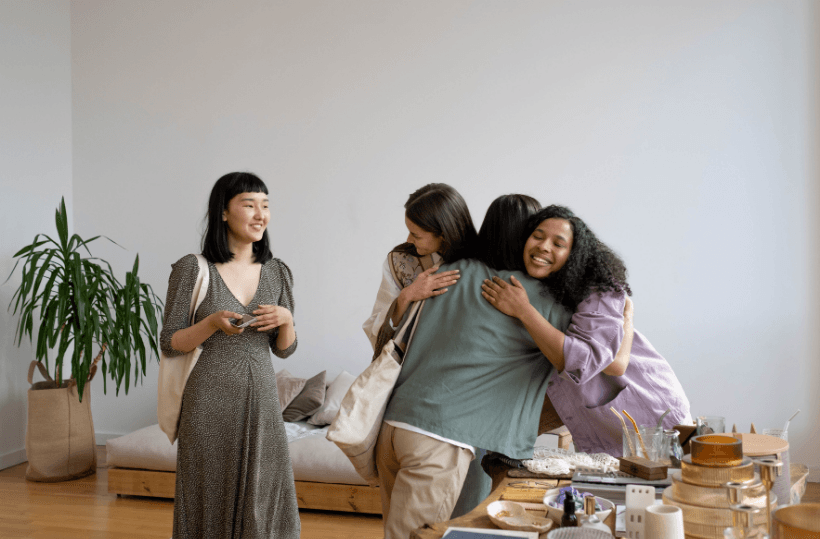 A small group of women greeting each other with a hug in a bright room